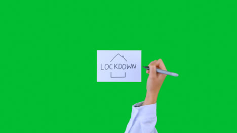 Arzt-Schreibt-Lockdown-Mit-Hausillustration-Auf-Papier-Mit-Grünem-Bildschirm